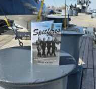 Book titled 'Sealifters' on a metal surface with military vehicles in the background